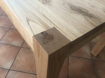 Vista ravvicinata del tavolo in legno di Castagno verniciato naturale, dal design moderno.