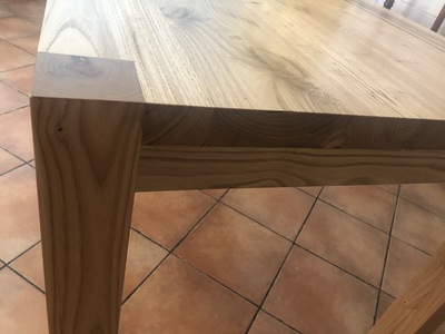 Vista ravvicinata del tavolo in legno di Castagno verniciato naturale, dal design moderno.