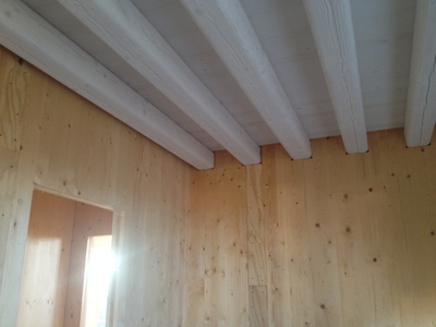 Tetto interno della casa in legno bio edilizia con vista di travi "uso fiume" bianche.