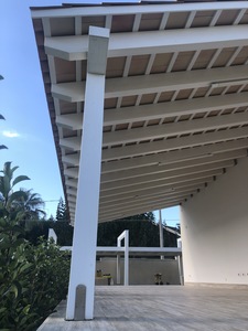 Vista laterale di una tettoia in legno Abete  lamellare impregnata bianco con listelli e mattoni a vista . Copertura finale con coppi siciliani, realizzata a Mazara del Vallo (TP)
