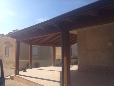 Vista laterale di una tettoia in legno lamellare Abete e perline con disegno costruttivo particolare a 1 falda con 2 diagonali, con copertura finale di  tegole, realizzata a  Marsala (TP)