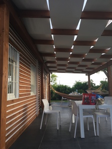 Casa in legno prefabbricata con pareti coibentati e pergolato esterno in legno e teli ombreggianti, realizzata a Petrosino (TP)