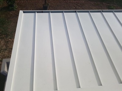 Vista parte superiore di una tettoia in legno lamellare Abete impregnata bianco con copertura finale in alluminio aggraffato complete di gronde e accessori, realizzata a Trapani (TP).