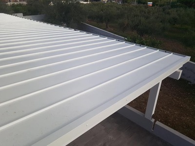 Vista parte superiore di una tettoia in legno lamellare Abete impregnata bianco con copertura finale in alluminio aggraffato complete di gronde e accessori, realizzata a Trapani (TP).